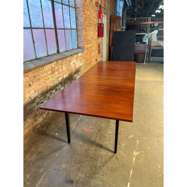 A stunning mid-century modern dining table designed by George Nelson for Herman Miller, featuring a richly figured...