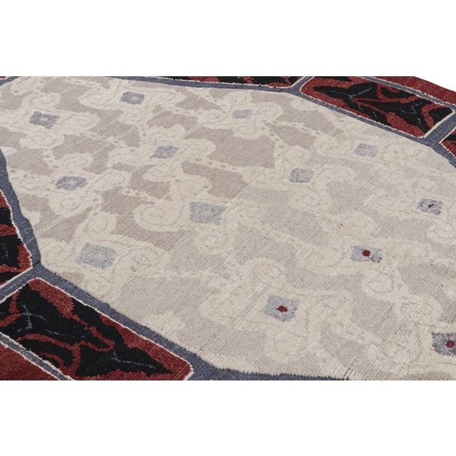 Hand-knotted in wool, this 6x9 French Art Deco rug features an interesting play of red and beige-gray in the all over...