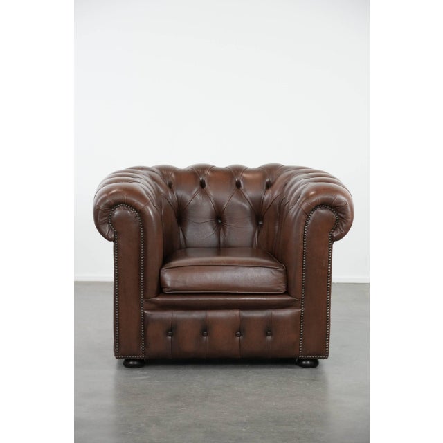 This magnificent brown cowhide Chesterfield club armchair in English style, finished with decorative studs. This...