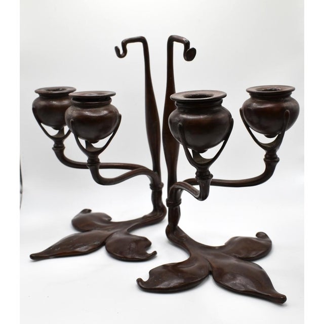 These are a pair of Tiffany Studios candlesticks. They are bronze with a Fleur-De-Lis motif base. They are stamped...