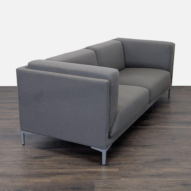 This CB2 loveseat features a modern, boxy design with clean lines and deep cushions for comfortable seating. Upholstered...