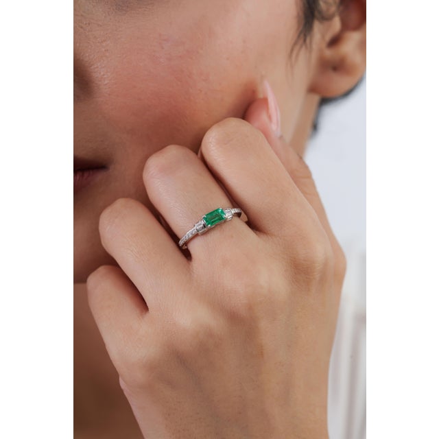 This East-West ring features a 0.61 ct natural Zambian octagon emerald, set in 14K white gold. Each measuring 6 × 3.5 mm,...