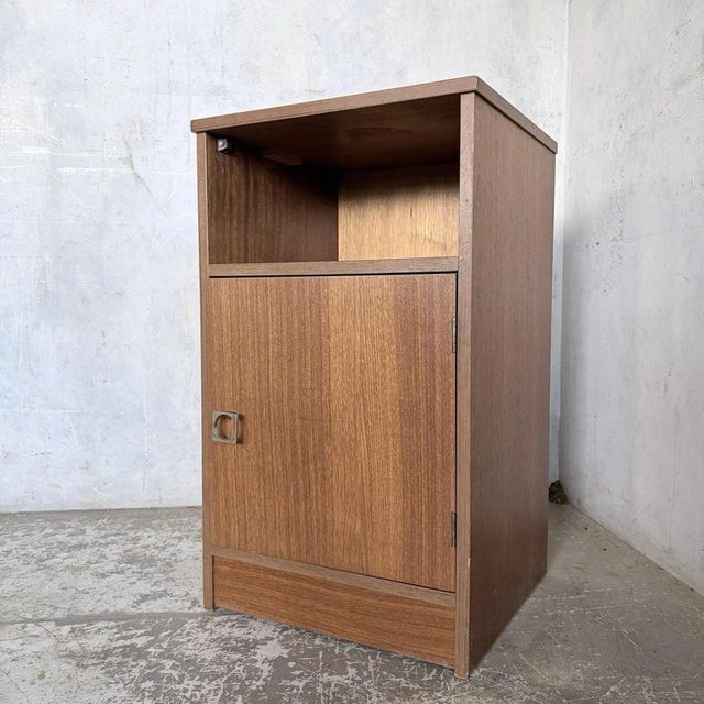 a compact mid-century american-style teak bedside cabinet with an open shelf for books and everyday essentials. The simple...