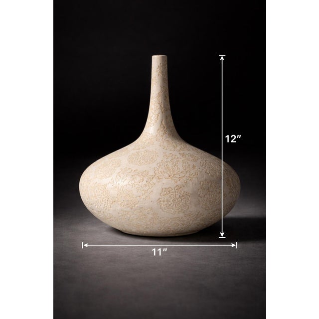 A beautifully sculptural ceramic vase featuring an all-over botanical relief pattern in soft neutral tones. With its wide,...