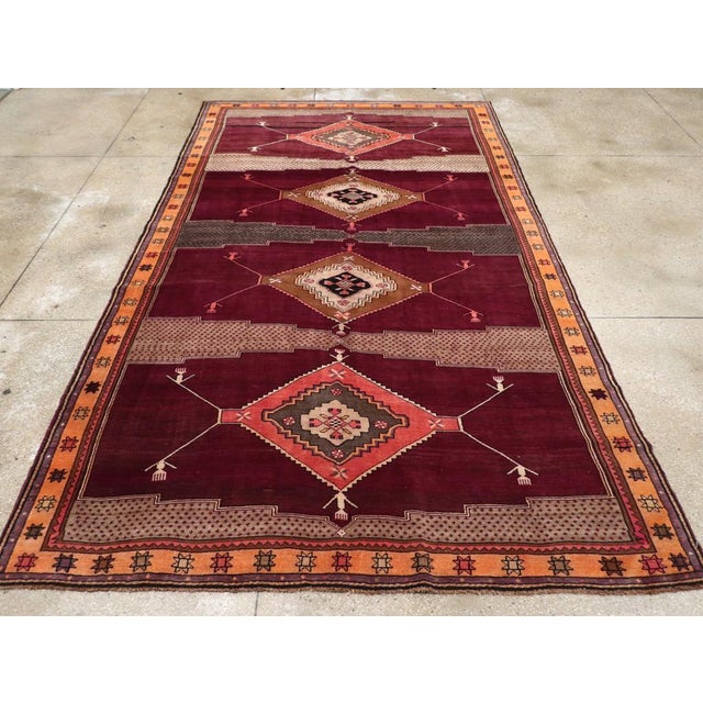 A vintage Turkish Anatolian tribal room size carpet, in long and narrow format, handmade during the mid-20th century....