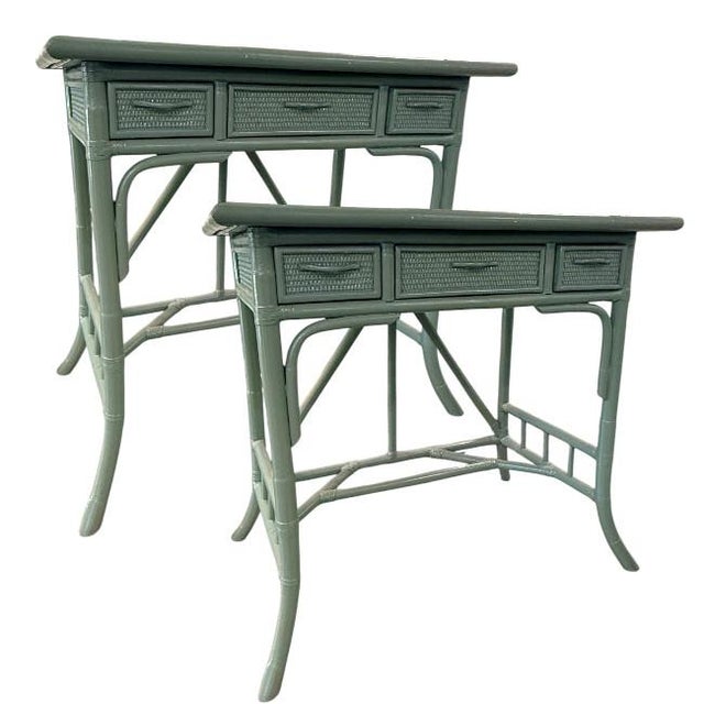 Charming pair of vintage rattan side tables featuring a sculptural bamboo-style frame and woven drawer fronts. Finished in...