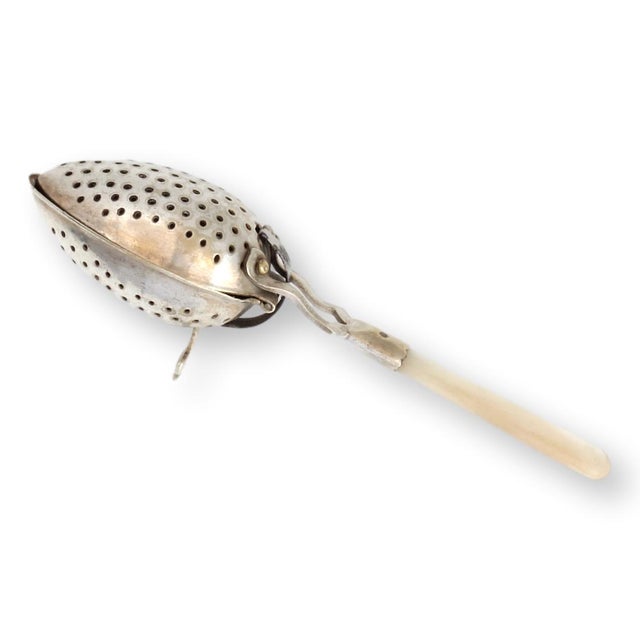 This rare antique English tea strainer features a beautiful mother-of-pearl handle, adding a touch of sophistication to...