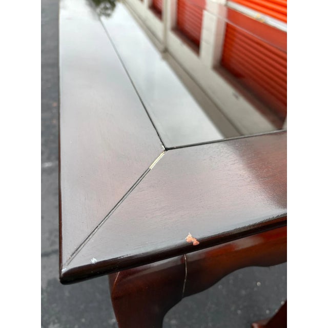 This elegant wooden console table features a sleek glass inset top and clean, classic lines. The rich dark wood finish...