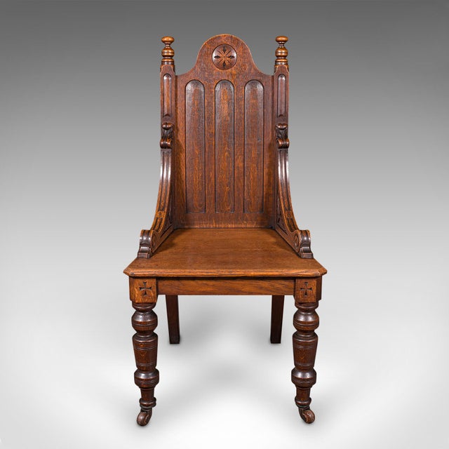 This is an antique Gothic Revival hall chair. A Scottish, oak baronial reception seat, dating to the Victorian period,...