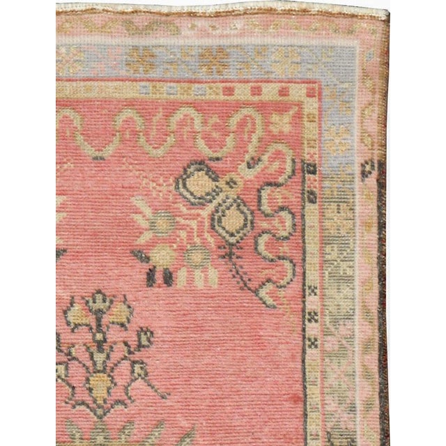A vintage Turkish Oushak throw rug. The rose-grey semi-open field displays a sand medallion with small stylized flower...