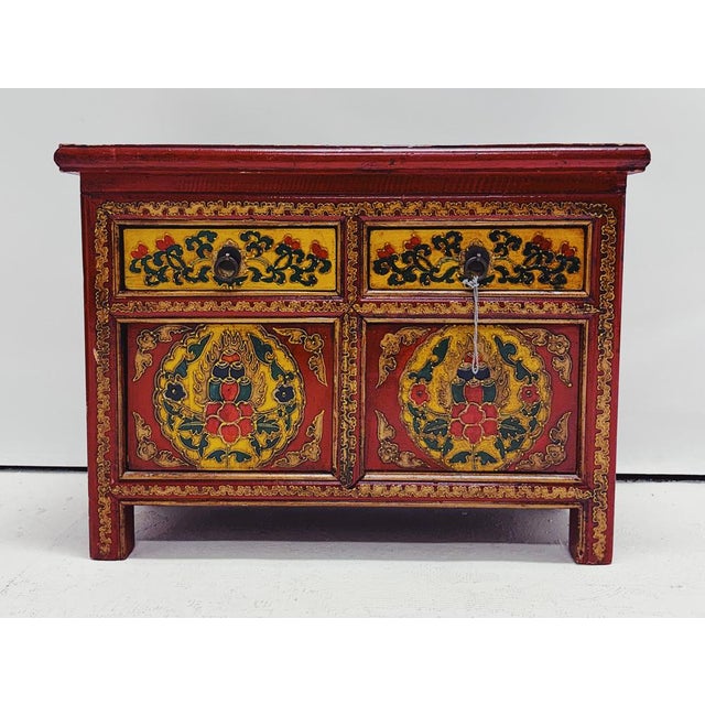 Set of two Tibetan bedside tables. The tables are hand-painted and feature decorative inlay work. Both tables have two...