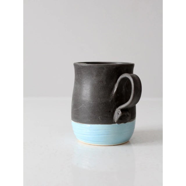 This is a handcrafted studio pottery mug by Nicky Ross of NStar Studio, dated 2012. The form is finished with a charcoal...