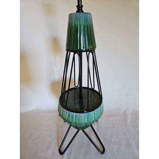 A pair of MCM Atomic wrought iron hairpin tripod teal green ceramic table lamps. Beautiful and rare set featuring a...
