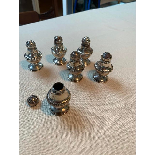 Six small silver salt and pepper shakers have their own velvet pouch.