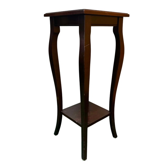 Elegant pedestal side table by The Bombay Company, crafted in dark-stained wood with a tall, slender silhouette. The...
