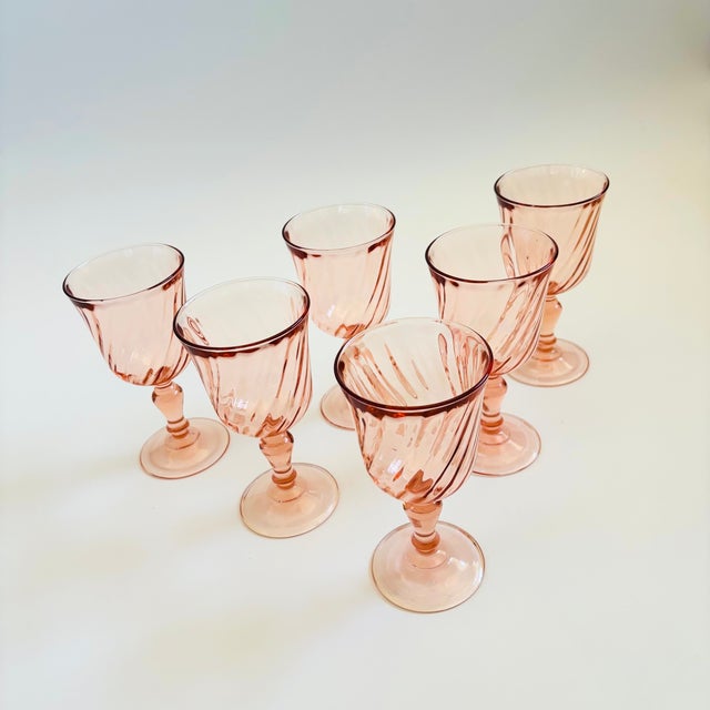 A set of 6 vintage wine glasses in a pale blush pink hue. Each glass has a lovely swirl design. Made in France by Arcoroc....