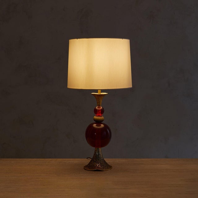 A 1970s Italian table lamp, reminiscent of designs by Pierre Casenove. Stacked blown glass spheres in rich oxblood red...