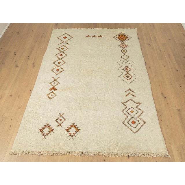 Wonderful Berber rug with long fringes from the 1960s. Cream-colored pile with patterns in brown, orange and beige tones....