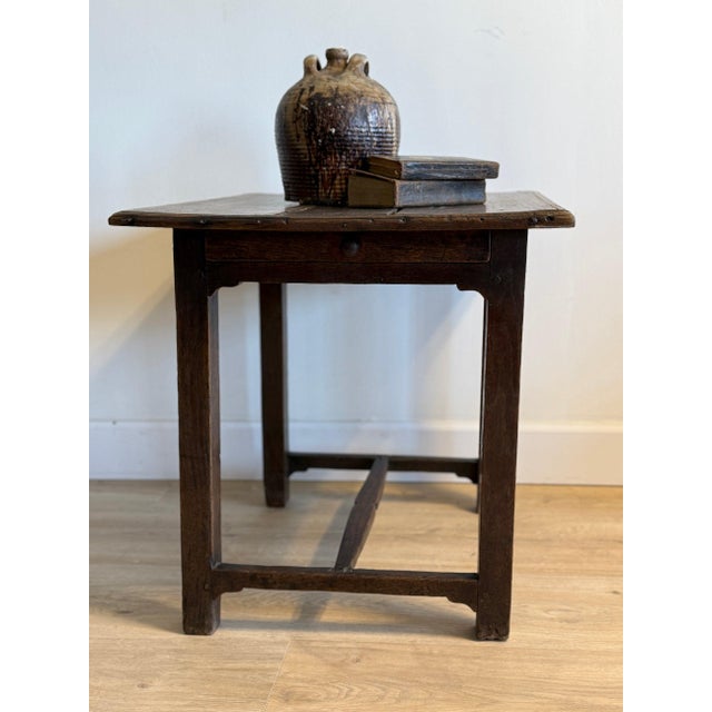 A late 17th to early 18th century English oak side table with a beautifully grounded, utilitarian form, featuring a single...