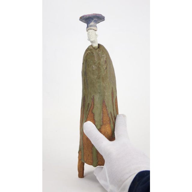 Figurative ceramic sculpture with wood-ash glaze, textured high-temperature clay and a porcelain head topped by a rusula-...