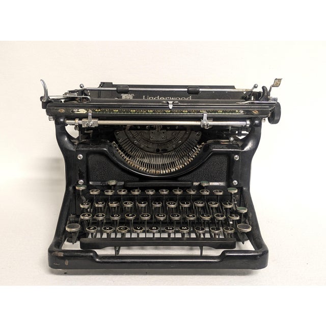 A 1938 Model 6 Underwood typewriter. The vintage typewriter has a black finish with closed sides. The typewriter has some...
