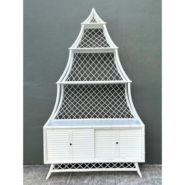 This vintage white rattan pagoda étagère combines airy open shelving with practical lower storage. Its tiered silhouette...