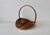 Vintage wicker catchall basket featuring a broad, shallow woven base and a tall arched handle. French-style, oval-shaped...