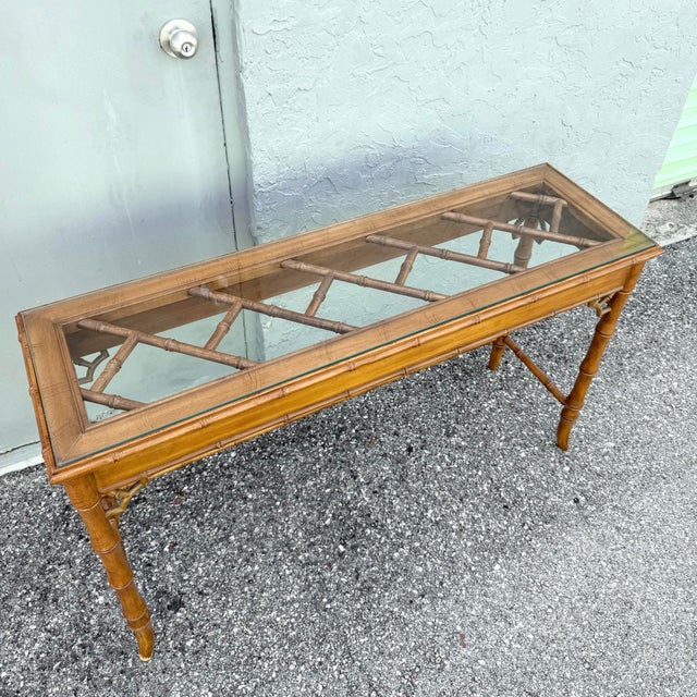 Vintage Boho Chic console table featuring an elegant faux bamboo frame with classic Chippendale-inspired details. The...