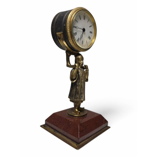 Interesting Chinese clock made of bronze, depicting a delicately sculpted Asian figure holding the clock face. The piece...
