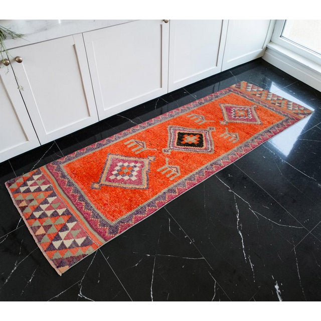 Woven by skilled artisans in Southeastern Anatolia during the 1970s, this vintage hand-knotted runner rug is a striking...