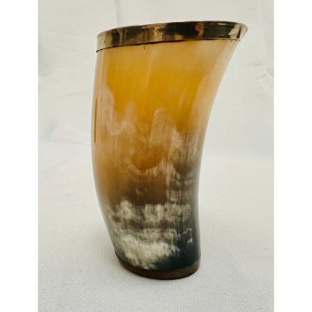 Natural horn cup with silvered mounted rim. The cup is lighter on one side and darker on the reverse. The cup has a...
