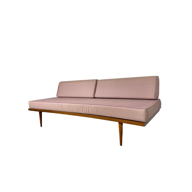 A wonderfully streamlined vintage mid-century modern sofa and daybed featuring a low wood platform frame, tapered legs,...