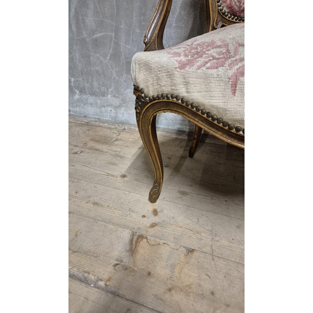 An elegant louis xv armchair dating from the 1740s, featuring a gracefully curved carved wooden frame, shaped backrest,...