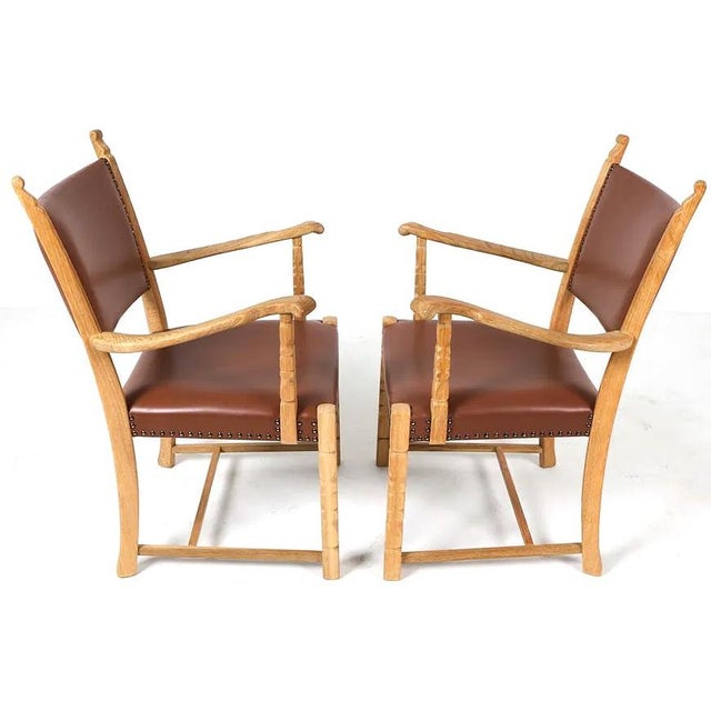 A fabulous pair of carved oak Danish Modern armchairs with leather upholstery and tacking accents. The chairs, while...