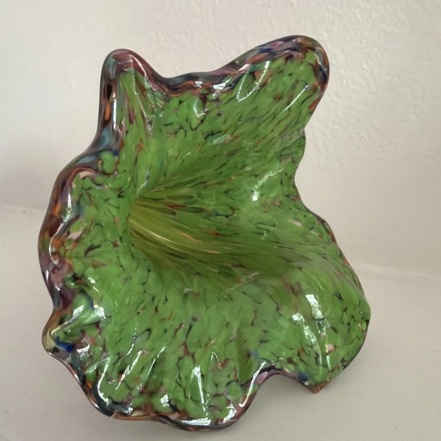 The product is a hand-blown Murano style glass figurine in the shape of a flower, featuring vibrant green and purple...