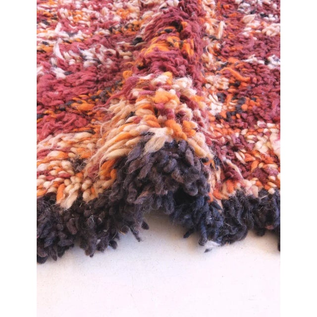 This handwoven wool rug, measuring 10.5 by 6.5 feet, embodies the spirit of the Beni Mguild tribe from Morocco’s Middle...