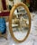 Elegant Italian style vertical oval wall mirror featuring an ornate gold leaf frame beautifully enhanced with decorative...