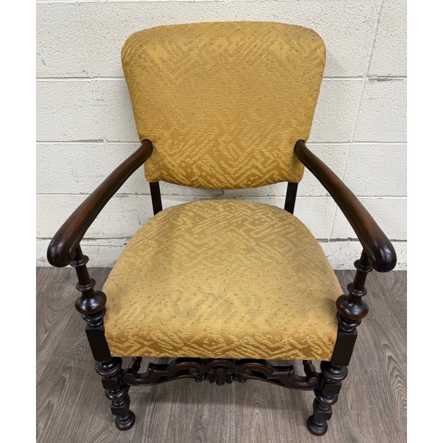 This is a vintage Spanish Revival or Renaissance Revival walnut armchair featuring graceful rolled arms, beautifully...