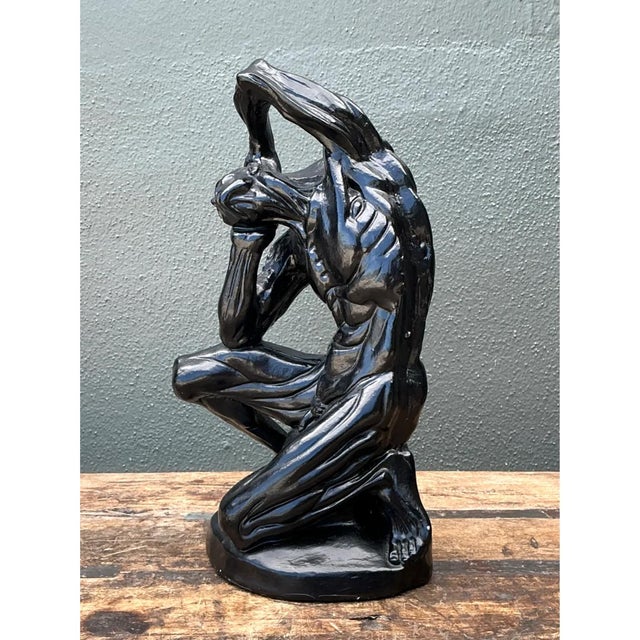 This expressionist sculpture captures a seated male figure in a deeply contorted, emotionally charged pose, one arm raised...