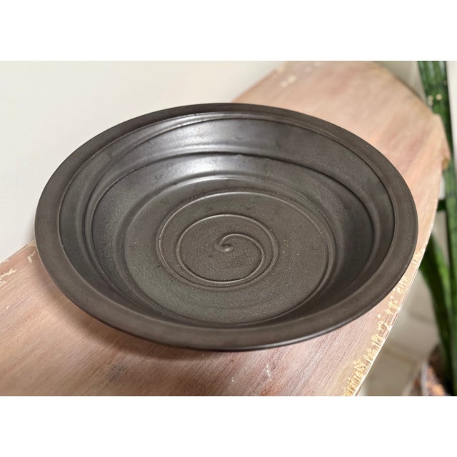 Chic, contemporary pottery bowl with a swirled motif. The finish is a satin black. Illegibly signed. Circa mid 20th century.