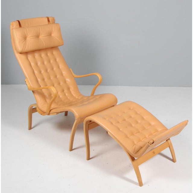 Bruno Mathsson Pernilla lounge chair with ottoman, original light leather upholstery. Frame in lacquered beech. Made by...