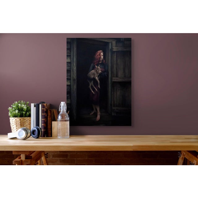 The artwork depicts a woman standing in a doorway, cradling a fawn, evoking a sense of tenderness and vulnerability. The...
