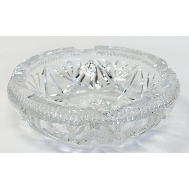 Vintage cut glass ashtray featuring star pattern to bottom of bowl surrounded by swirls. Four rounded notches to...