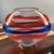 This stunning Italian hand-blown art glass vase features a unique oval shape with vibrant red and blue horizontal bands....