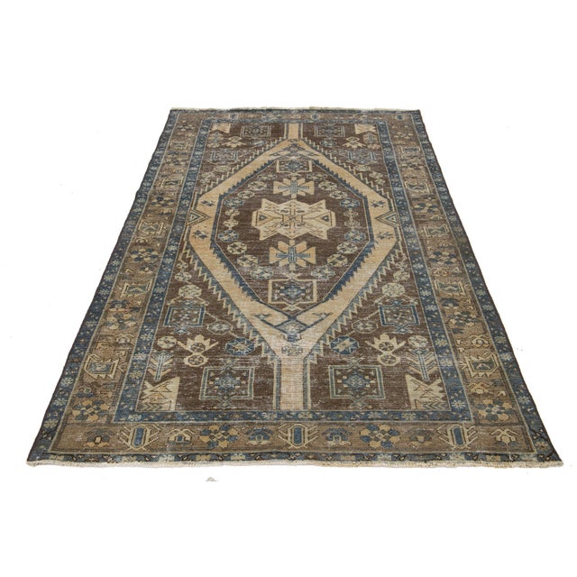 This captivating vintage Persian wool rug showcases a primary brown color with stunning beige and blue all-over accents....