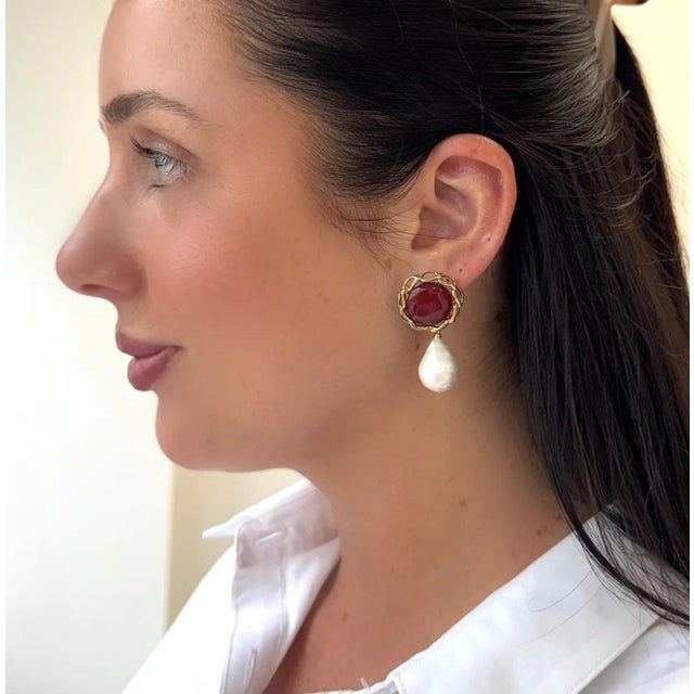 This vibrant red triplet is paired with a freshwater pearl drop. Great way to sport the color of the season. For pierced...