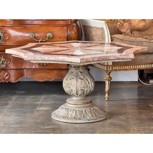 Octagonal low table with a stone top set over a central pedestal base. The top has a faceted octagonal outline with a...
