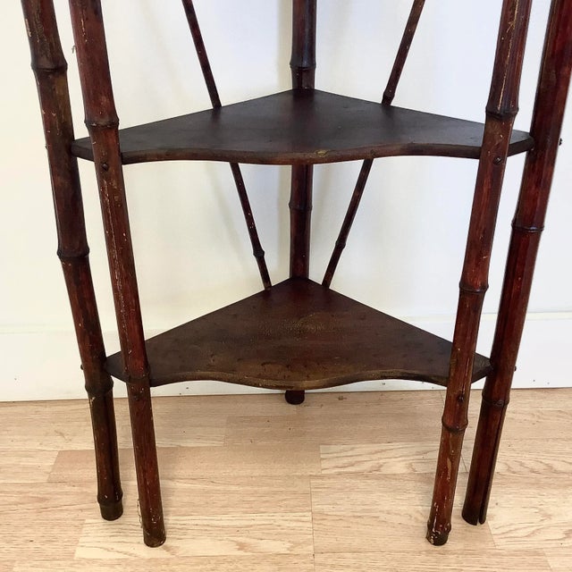A classic British Colonial bamboo corner shelf in a burnt Mahogany stained finish. The design is ball and sticks with four...