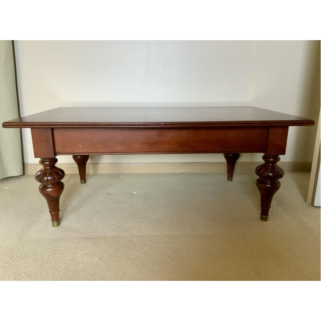 A rectangular mahogany coffee table with a rich, dark wood finish and visible grain across the top, a single long drawer...
