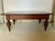 A rectangular mahogany coffee table with a rich, dark wood finish and visible grain across the top, a single long drawer...
